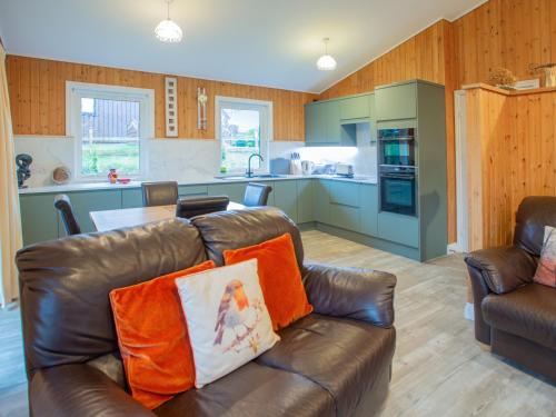 a living room with a leather couch and a kitchen at Amber Nook in Tirril