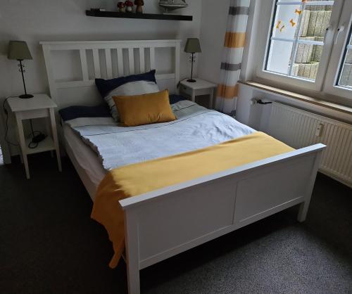 a bedroom with a white bed with a yellow blanket at Cozy basement apartment in Mettmann in Mettmann