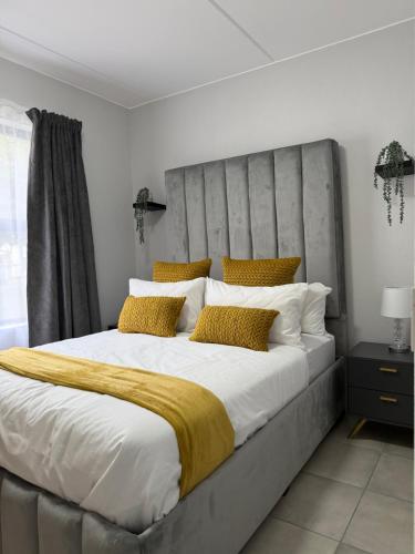 een slaapkamer met een groot bed met gele kussens bij Elevare suites in Nelspruit