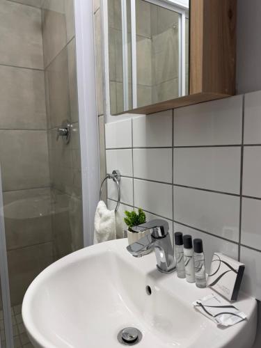een badkamer met een witte wastafel en een douche bij Elevare suites in Nelspruit