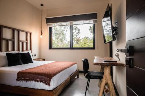 Un dormitorio con una cama y un escritorio y una ventana. en 4BDR Luxury Villa 2 Private Pools 10 min Beach & Zamna, en Tulum