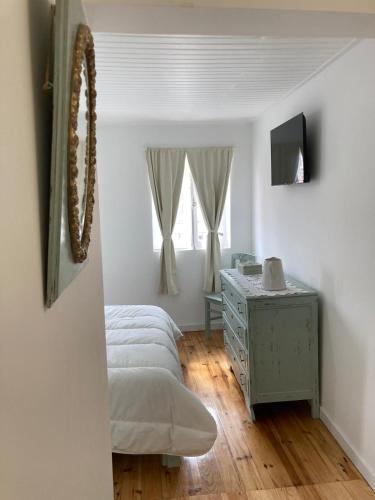a bedroom with a bed and a dresser and a window at Melro-d' água in Manteigas