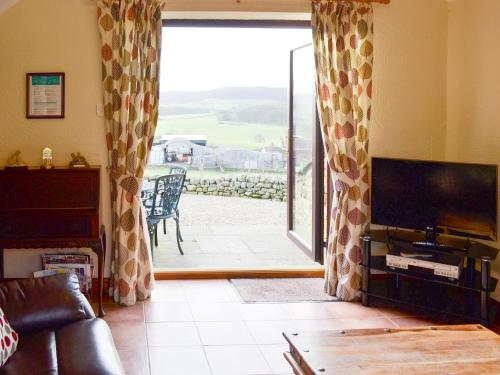 a living room with a television and a sliding glass door at Swallows Nest-18094 in Cloughton