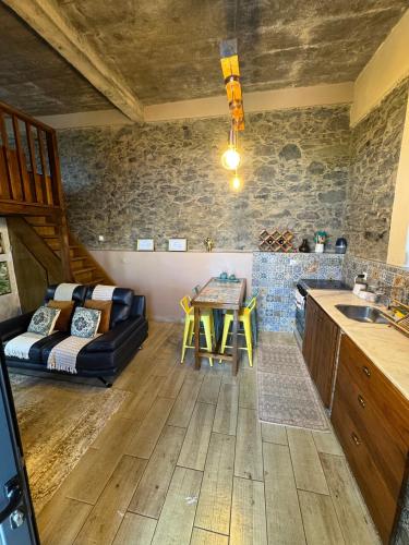 a kitchen and living room with a couch and a table at Victoria Tiny Stone House in Ponta do Pargo
