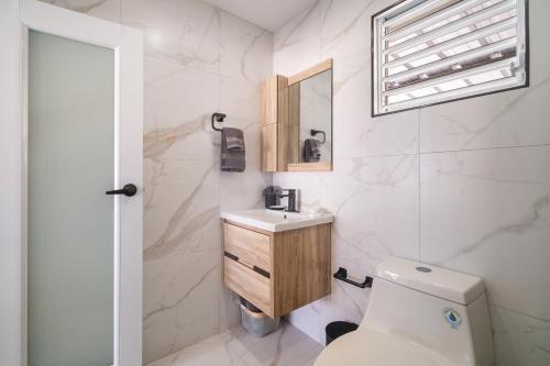 une salle de bain avec toilettes, lavabo et miroir dans l'établissement SunJoy Gateway Lux 2 bedroom House by PH, à Carolina