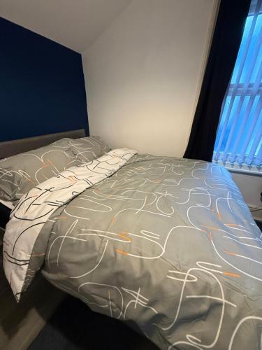 a bedroom with a bed with a blanket with drawings on it at City Apartment in Litherland