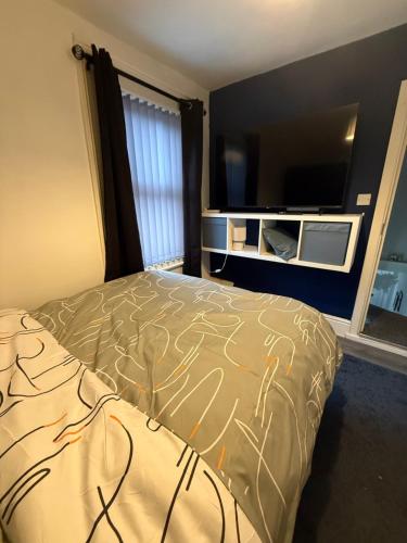 a bedroom with a bed and a flat screen tv at City Apartment in Litherland
