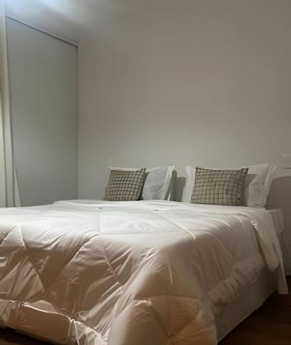 un lit blanc avec des draps et des oreillers blancs dans l'établissement Flat Ruanda para casal em meio à natureza!, à Nova Friburgo