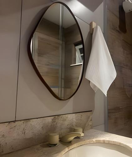 une salle de bain avec un miroir et un lavabo dans l'établissement Flat Ruanda para casal em meio à natureza!, à Nova Friburgo