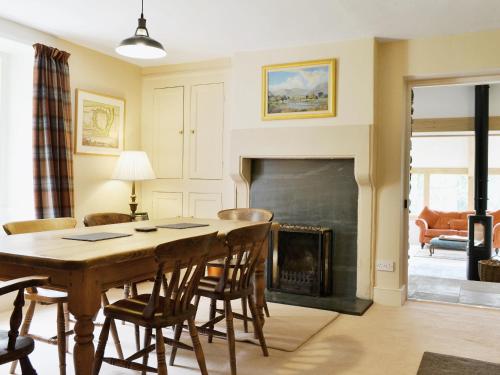 una sala de estar con una mesa y una chimenea en High Birch Close, en Penruddock