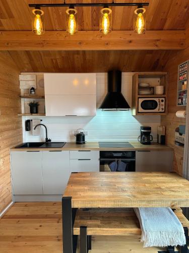a kitchen with white cabinets and a wooden ceiling at The Cabin log fire cosy home in Folkestone