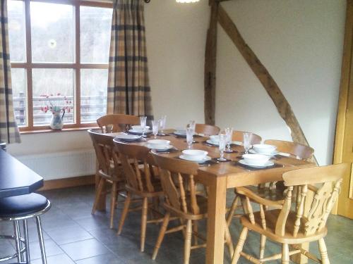 a wooden table with chairs and a table and a window at Cwm Corn Barn - Hw7662 in Mochdre