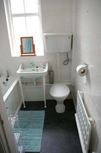 a bathroom with a toilet and a sink and a window at The Cottage in Etal