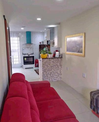 a red couch in a living room with a kitchen at Quarto de descanso na baixada in Mesquita