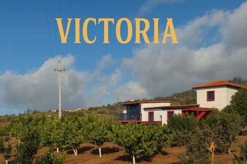 a sign for a vineyard with a house and trees at Victoria Tiny Stone House in Ponta do Pargo