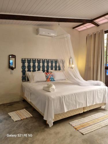 ein Schlafzimmer mit einem weißen Bett mit Moskitonetz in der Unterkunft Cabana CasaBah in São Sebastião