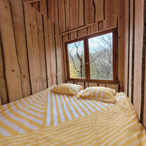 uma cama num quarto de madeira com uma janela em Cabane octogone sauvage - Octogonia, Ardèche em La Rochette
