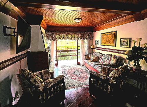 ein Wohnzimmer mit einer Couch und zwei Sesseln in der Unterkunft APART Deluxe Campos do Jordāo com lareira in Campos do Jordão