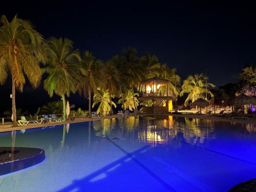a large swimming pool with palm trees at night at La Kaz a lò in Le Diamant