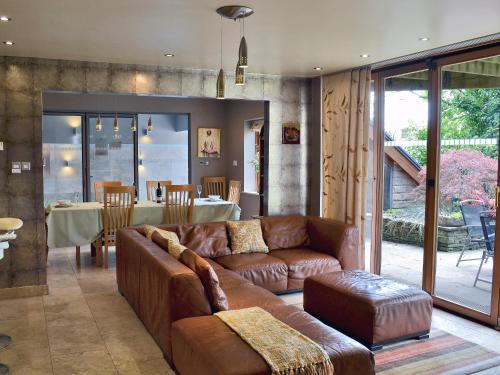 ein Wohnzimmer mit einem braunen Sofa und einem Tisch in der Unterkunft Moorecroft in Buxton