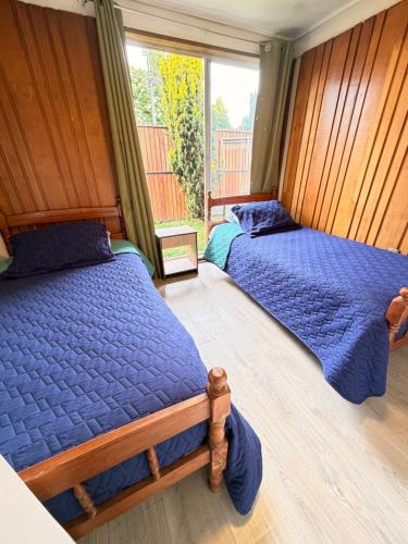 a bedroom with two beds and a window at Casa Cypresses in Temuco