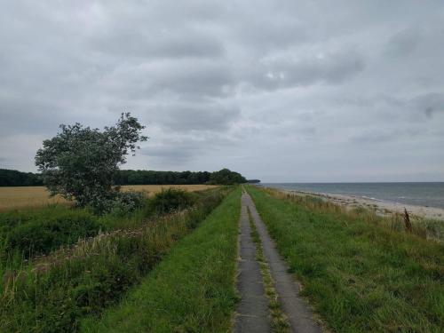 a dirt road next to the ocean on a cloudy day at 2 person holiday home in Otterup in Otterup