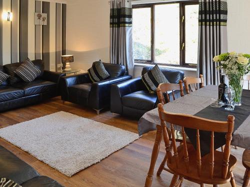 a living room with a table and leather furniture at River View Villa - Cv44 in Saint Cleer