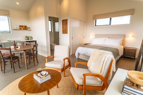 a bedroom with a bed and a dining room at Harvest Rise Vineyard Cottage in Pahautea