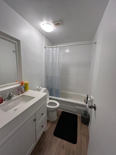 een witte badkamer met een toilet en een wastafel bij Modern Suite, 1 Guest Room in St. Catharines