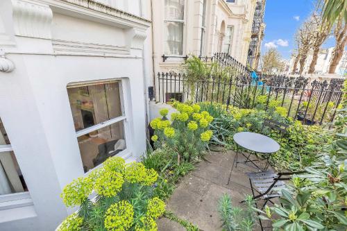 a patio with a table and flowers in front of a building at The Coastal Den By My Getaways in Brighton & Hove