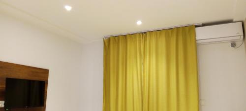 ein gelber Vorhang in einem Raum mit einem Fernseher in der Unterkunft Résidence touristique marcadal by Mon rêve in Fort de lʼEau