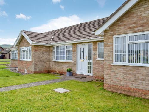 a brick house with a white door at Gwynt Y Môr in Tywyn
