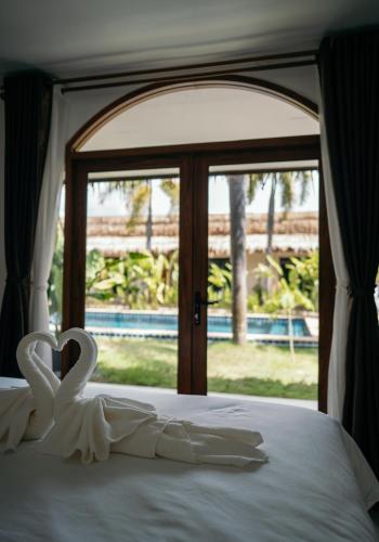 two swans sitting on a bed in front of a window at TALI BOUTIQUE Hotel in Ao Nang Beach