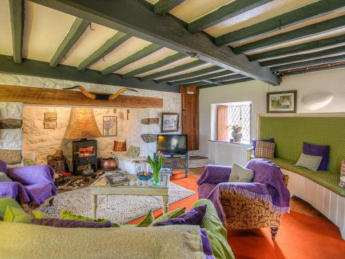 a living room with purple chairs and a fireplace at Hen Dy-Qc56 in Dolbenmaen