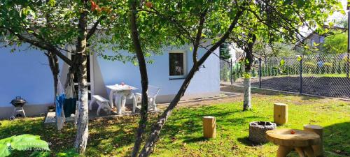 a small white house with a table and some trees at Noclegi W Sadzie in Rajcza
