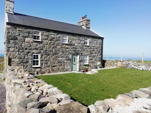 an old stone house with a stone wall at Eithinog Ganol in Llandwrog