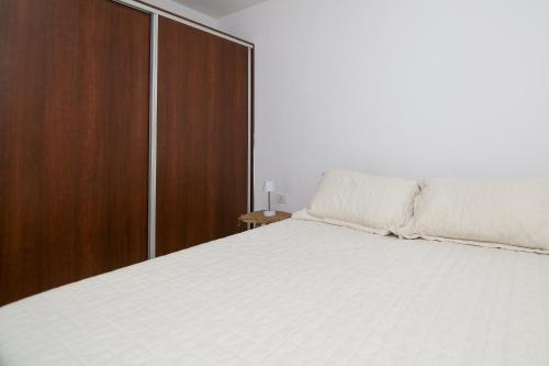 a bedroom with a white bed and a wooden cabinet at Departamento céntrico 25 MAYO I - Santa Fe in Santa Fe