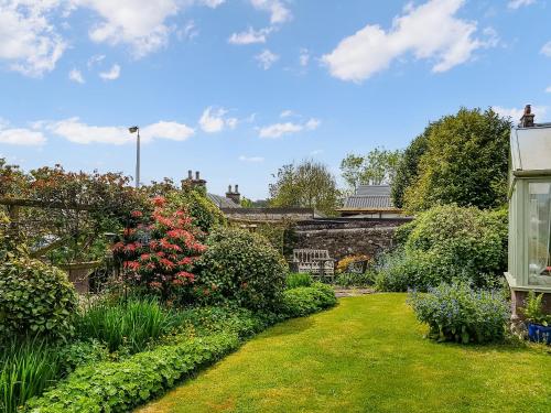 einen Garten mit bunten Blumen und einem Gebäude in der Unterkunft Ivy Cottage in Crieff