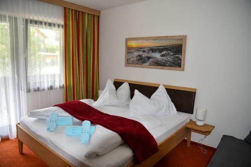 a bedroom with a white bed with a red blanket at Alpenhotel & Aparthotel Lanz in Hohentauern