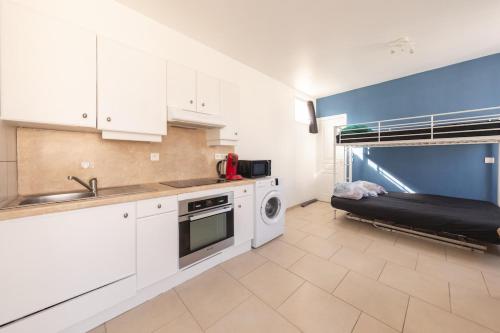 a kitchen with white cabinets and a bed in the background at Cénoslocs Aulnay for 6-7 people close to CDG in Aulnay-sous-Bois