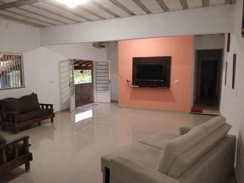 a living room with a couch and a tv on a wall at Chácara Amorim in Mairiporã