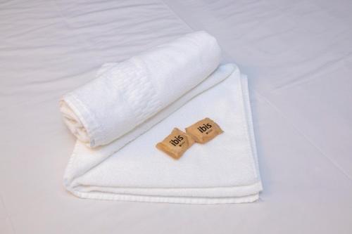 two wooden blocks on a white towel on a bed at ibis budget Divinopolis in Divinópolis