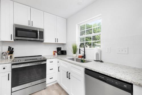 a white kitchen with a sink and a microwave at Stylish Queen City Getaway in Camp North End in Charlotte