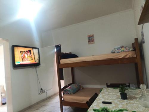 a bedroom with bunk beds with a tv on the wall at Pousada Praia Grande Apartamento Familiar in Praia Grande