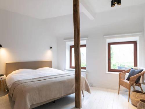 a white bedroom with a bed and a chair at Holiday home in the heart of Hasselt in Hasselt
