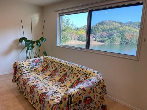 a living room with a couch and a large window at ゲストハウス坂の上のソルティーズ in Kainan