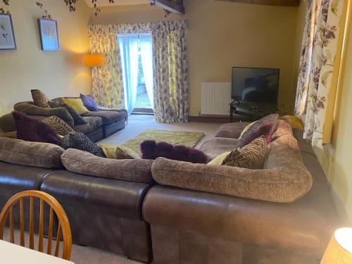 a living room with a large brown leather couch at Lily Rose Cottage in Lanercost