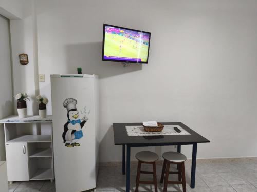 a kitchen with a table and a tv on the wall at Flat no coração de Guarapari,150 metros da praia com vista encantadora in Guarapari