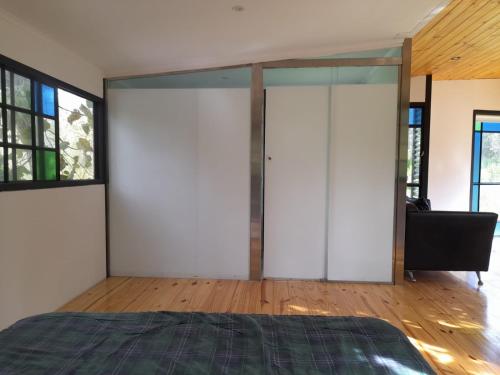a bedroom with white walls and glass doors at La casita del bosque en Muelle Delta Arias in Tigre