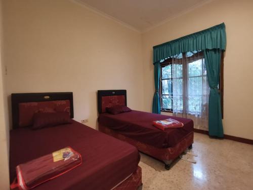 a bedroom with two beds and a window at Villa Graha Permata 1 in Batu
